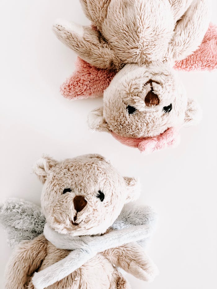 Two cute plush teddy bears with scarves on a pastel background, perfect for nursery decor.